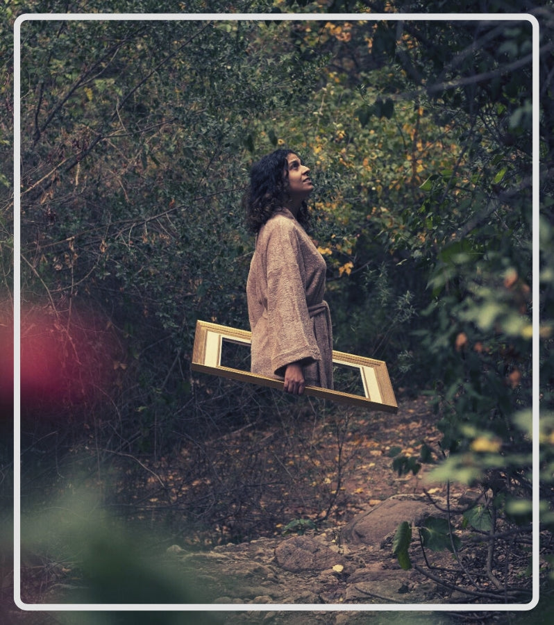 Fotografía artística: Mujer saliendo de un marco en albornoz en medio del bosque