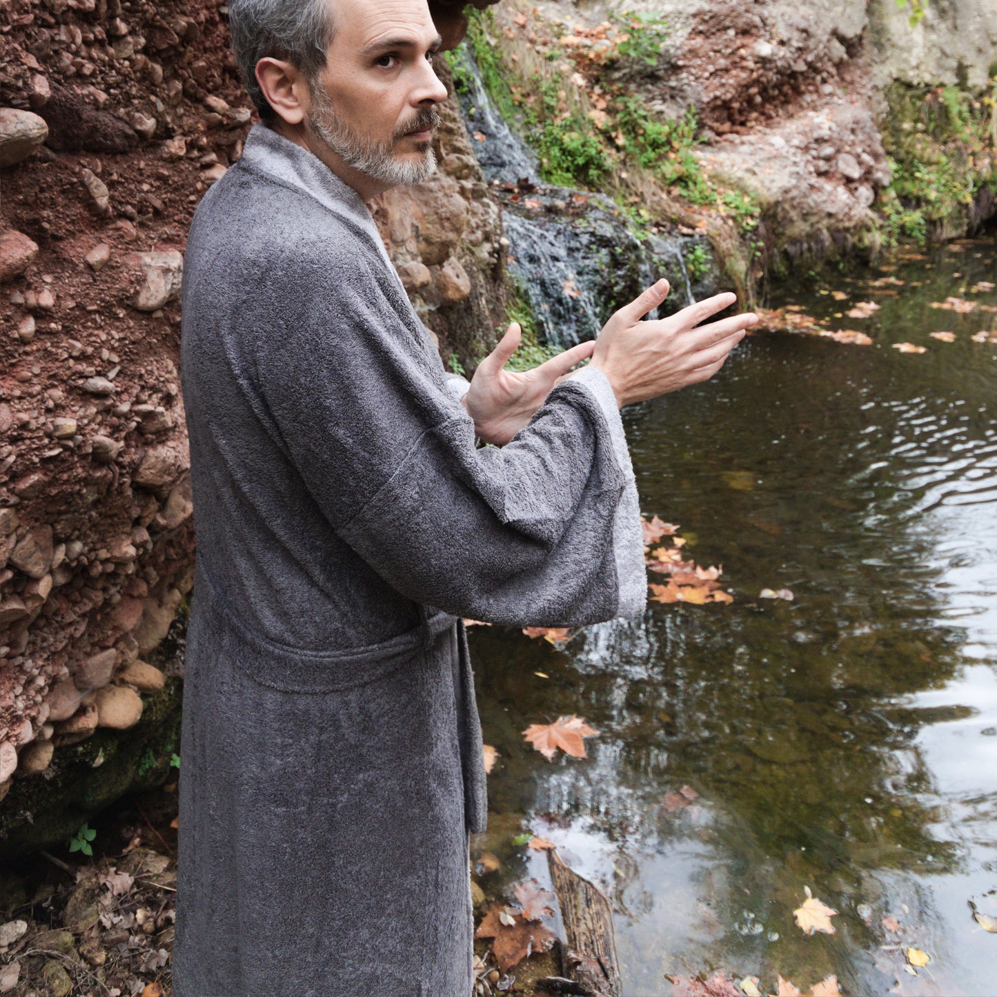 Hombre junto a un río en albornoz kimono gris
